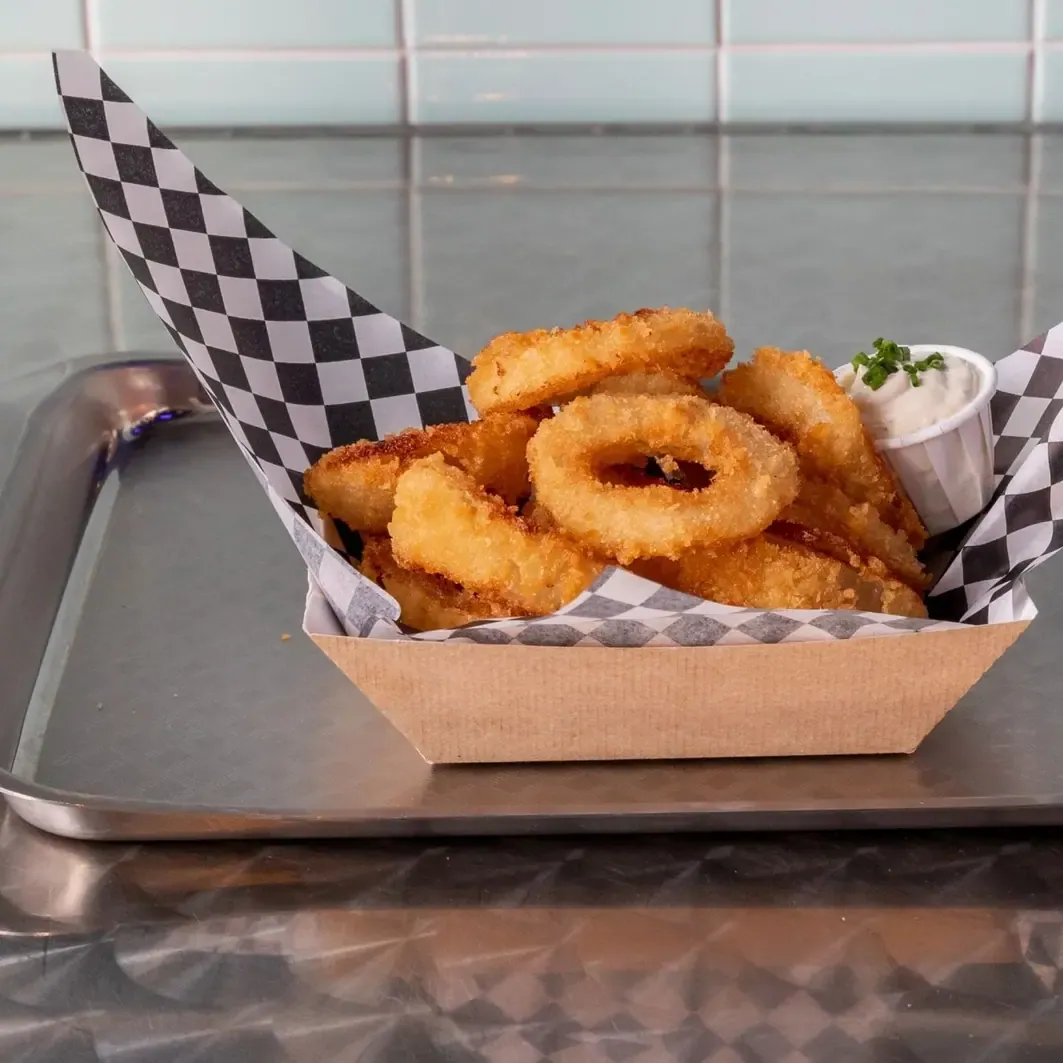 Aros de cebolla caseros con dip de ranch, sobre papel a cuadros